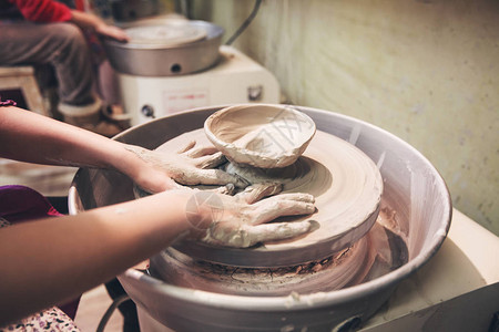 在陶瓷工作室车间的陶瓷车轮上塑造粘土的年图片