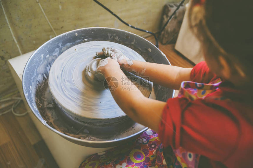 在艺术讲习班上小女孩在陶器车轮上塑图片