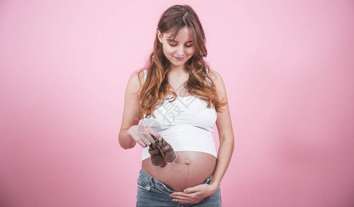 孕妇概念带婴儿拖鞋的孕妇手握着婴儿拖鞋图片