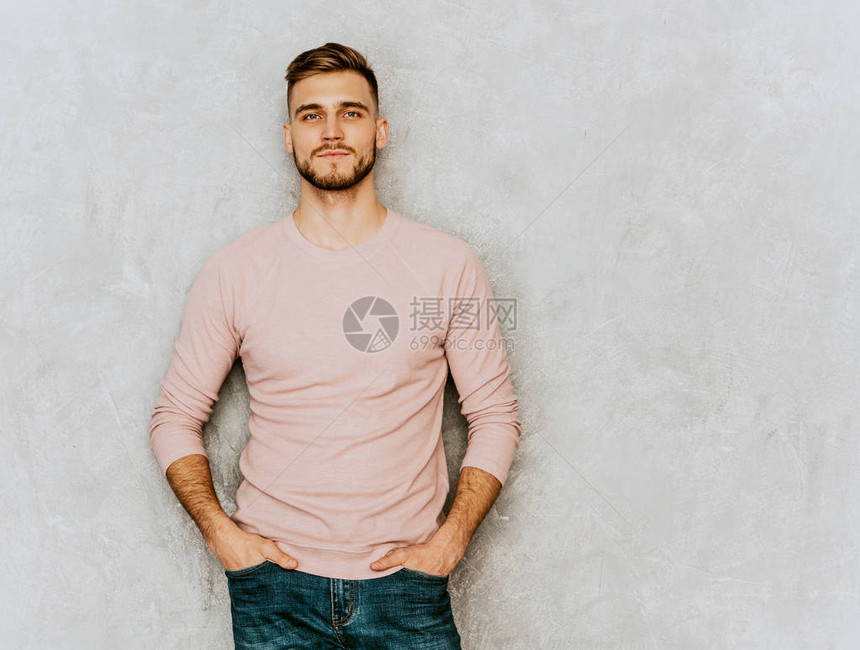 穿着休闲夏季粉红色衣服的英俊微笑时髦lumbersexual商人模型的肖像摆在灰色墙壁上的图片