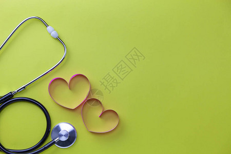世界卫生日背景保健和医疗背景概念的听诊器与心丝带在黄纸背景复制空图片