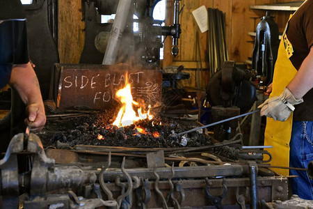 蹄铁湾几个铁匠在用一把旧铸造的炉制热熔金属背景