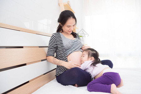 亚洲小女孩拥抱和倾听怀孕母图片