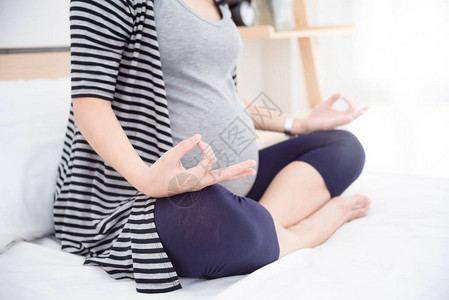孕妇在室内锻炼的躯干特写镜头怀孕的健身女人坐在瑜伽盘腿姿势怀图片
