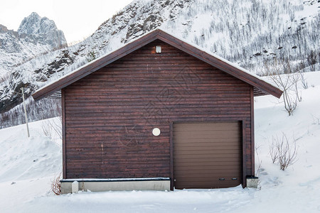 下去雪山上带卷门的棕色木制仓库背景