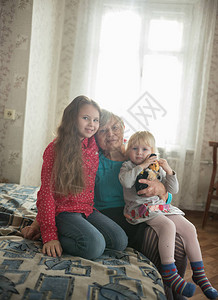 坐在床上的幸福家庭两个女孩和祖图片