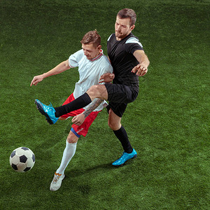 足球运动员在绿草背景下抢球职业男子足球运动员在体育场运动适合跳跃的人在游戏中的动作背景