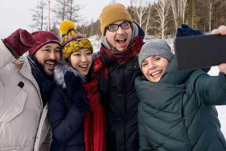 四个快乐的年轻人在冬季户外玩乐时拍自照片图片
