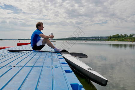 排行训练后坐在码头和饮用水上的年轻运动员图片