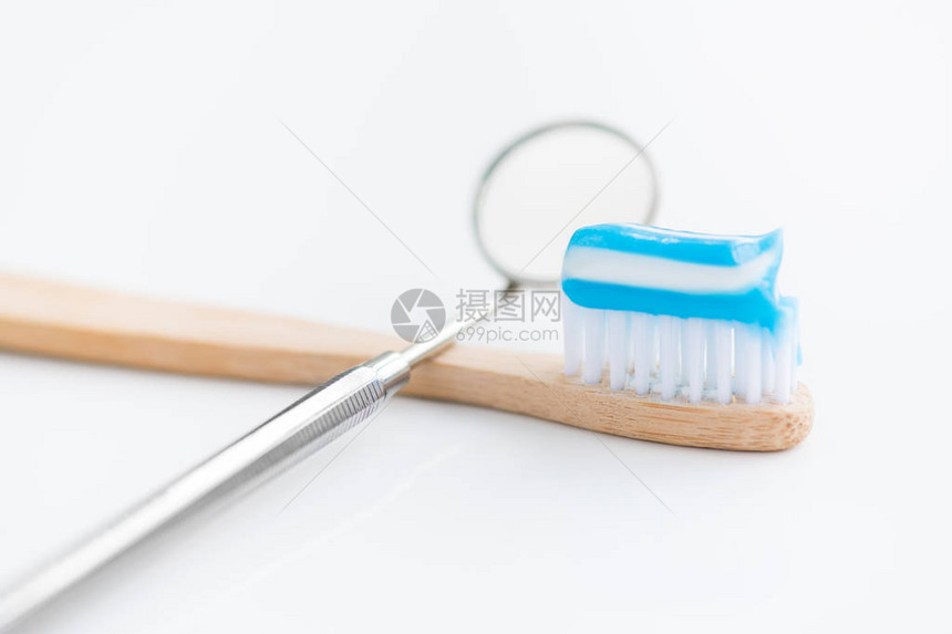 白色背景牙科和牙齿护理概念的牙刷旁边的口腔镜特写镜头图片