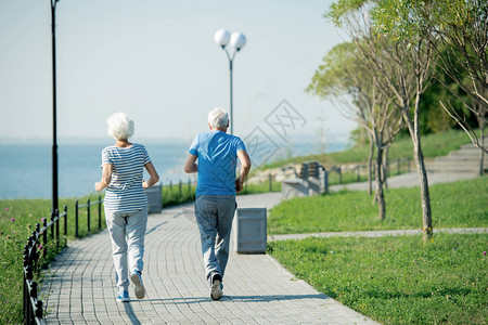 活跃的老年夫妇在海滨露天影印空间公园车道上奔图片