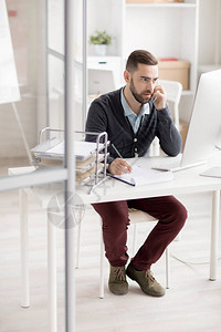 业务经理在现代办公室坐在办公桌前与客户通过电话交谈的全长肖图片