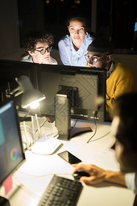 3人夜间在黑暗办公室复制空间工作时使用计算机的高角度背景图片