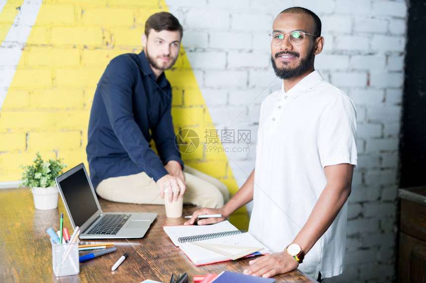两名男同事在现代办公室桌子上用笔记本电脑和笔记板一起计图片