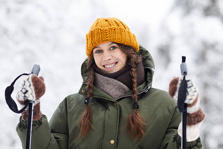 美丽的年轻女子在冬季森林滑雪的肖像看着摄影图片