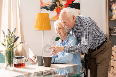 使用笔记本电脑在家一起在线购物复制空间的现代老年夫妇图片