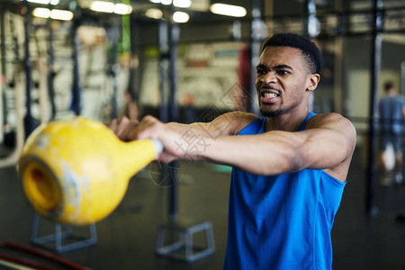 年青健壮的运动员在健身中心或健身房与重型小叮当一起锻图片