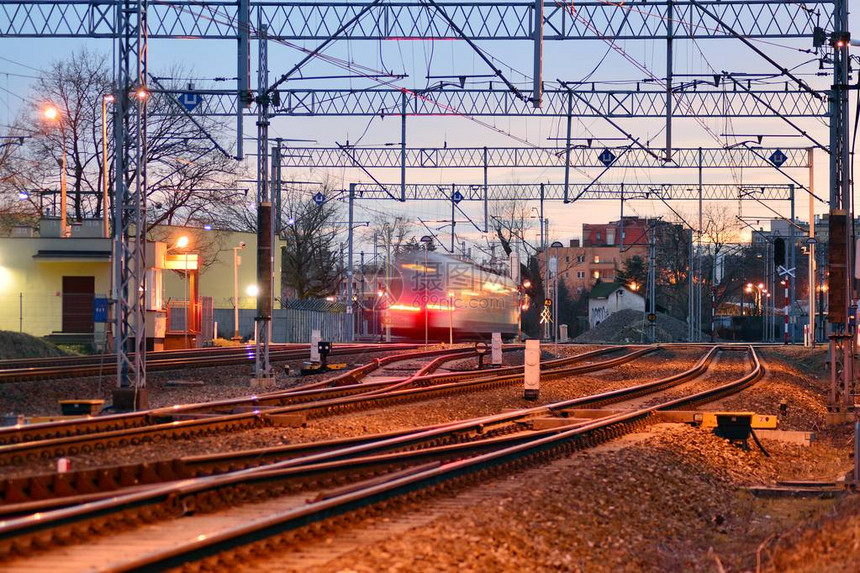 日出时火车轨上的客运列车图片