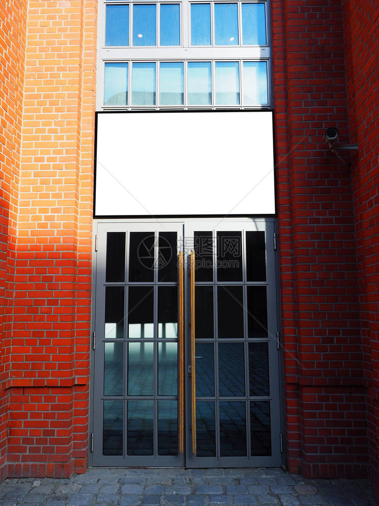 一栋带金属门的旧建筑正面空的白招牌图片