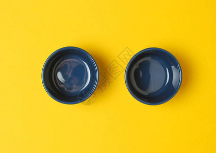 黄色背景上的两个蓝色珐琅碗图片