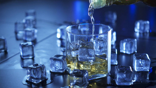 用冰块将酒精饮料倒入玻璃杯中图片