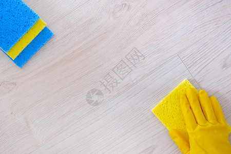 手持黄色橡胶防护手套清洁地板和家用抹布图片