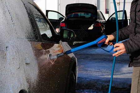 男子在户外洗车时洗橙色汽车在自助洗车时图片