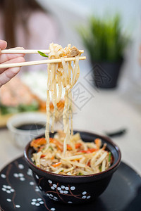 热汤面近距离的人类手拿面条从碗里用筷子和背景