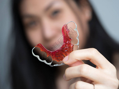 美丽的亚洲病人女在牙科诊所拿着正畸保持器的肖像图片