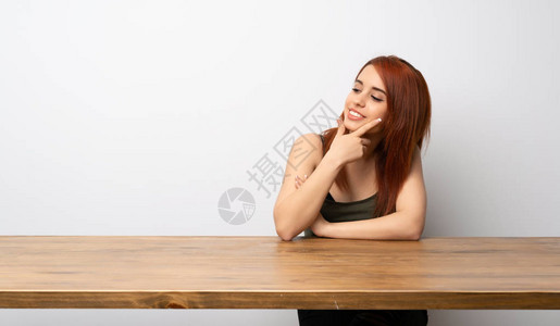 坐在办公桌前的年轻红发女人看着一边图片