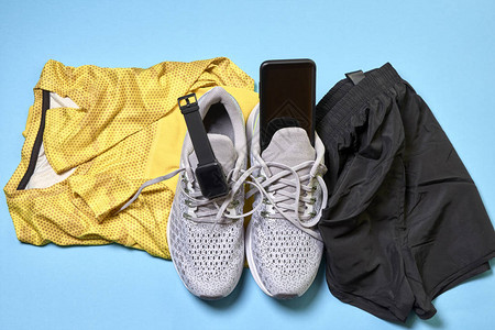 穿着短裤黄色衬衫和蓝底技术配件的跑鞋图片