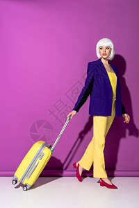 穿假发黄色手提箱紫色背景和黄色皮箱的图片