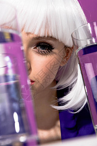 戴着白色假发的女孩戴着紫色背景的水杯图片