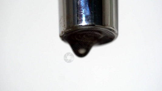 从水龙头孔滴水的特写镜头水滴从白色隔离背景上关闭不良的水龙图片