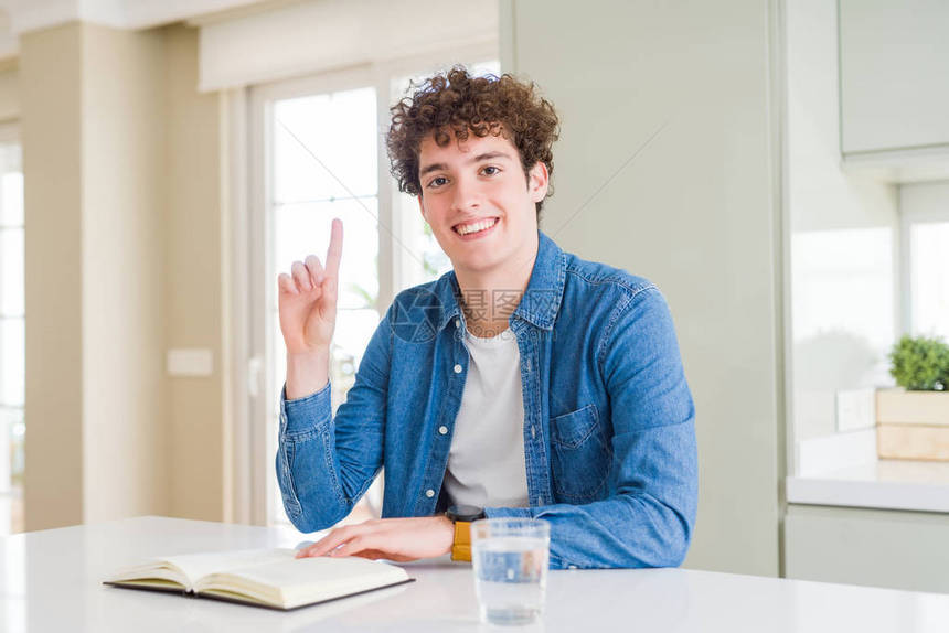 在家里读书的年轻男子惊讶于一个想法或问题用快乐的脸对着手指图片