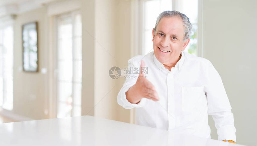 英俊的老人在家微笑着友好地握手作为问候和欢迎成功的生意成图片