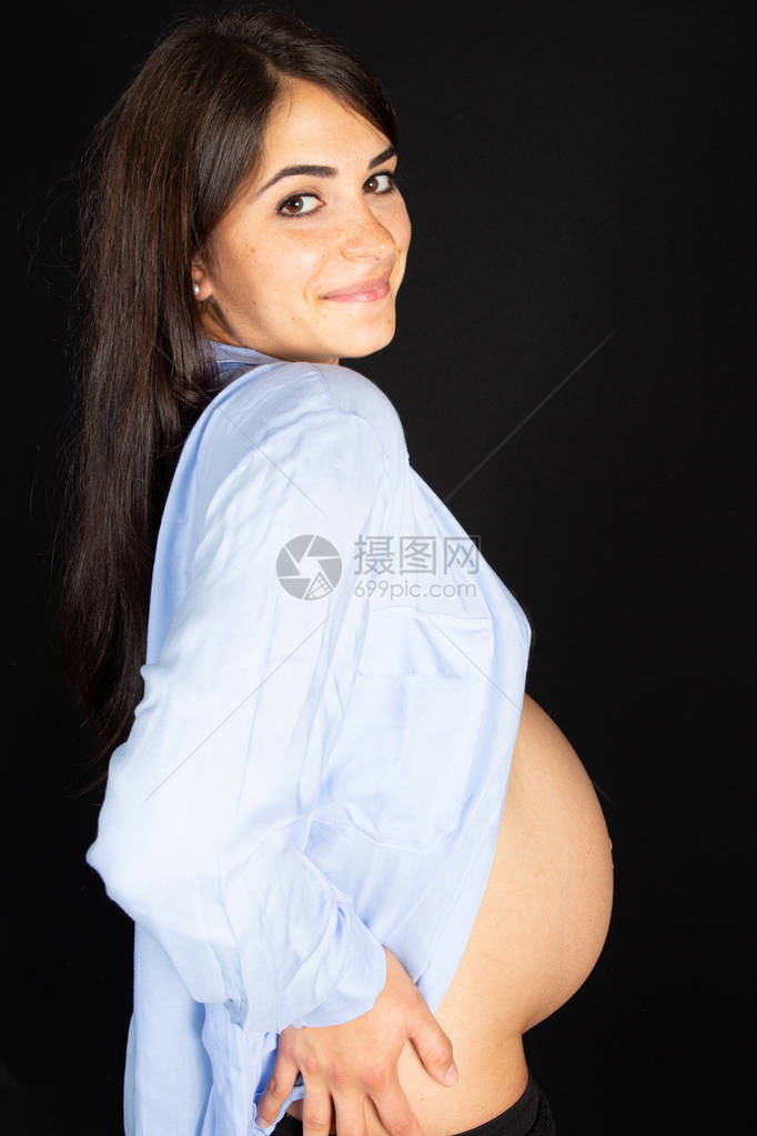 孕妇在黑背景下抚摸腹部的快乐孕妇健康怀孕图片