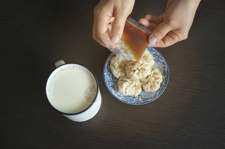 女人拿着家常酱油配中式点心舒麦和豆浆背景图片