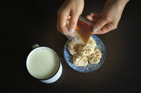 女人拿着家常酱油配中式点心舒麦和豆浆背景图片