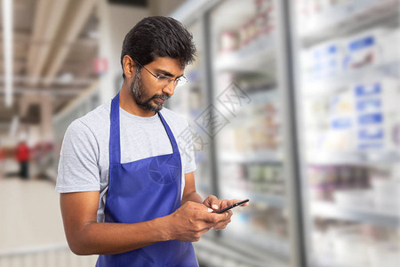 印度男超市或超市员工在电话上发短信图片