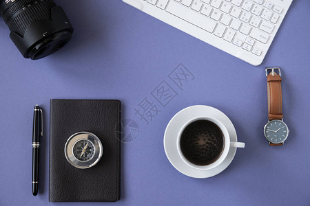 平面化办公桌顶部视图或平面是蓝色背景白键盘咖啡杯黑笔记本皮表金属背景