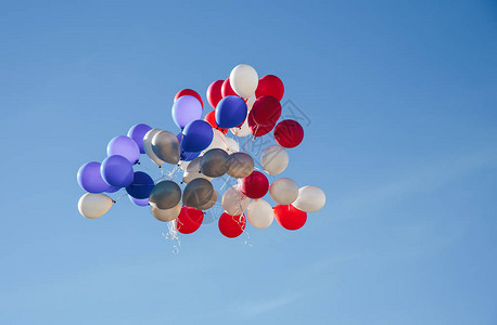 一束五颜六色的节日气球在天空中五彩气球在蓝天背景下的城市节日孩子们在天空中释放了很多背景图片