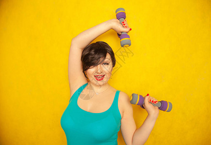 穿着蓝色T恤短发的胖快乐的情感女孩用哑铃做运动身体健康图片