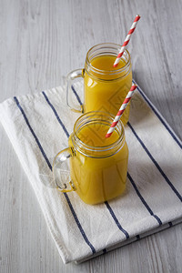 玻璃罐子里的新鲜橙汁在白色木制背景上图片