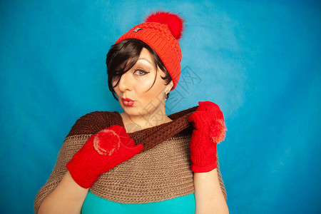 蓝色工作室纯色背景上穿着时尚红色针织冬帽和温暖漂亮手图片