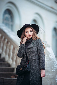 年轻美眉化妆完美红嘴唇戴黑帽子和灰大衣穿黑裙子在evi图片