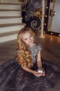 漂亮的小女孩靠近新年树漂亮的女孩在圣诞树附近等待假期的裙子室内装饰图片