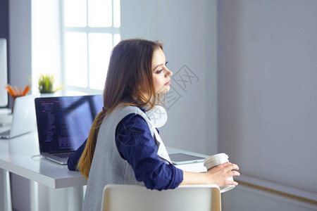 耳机中专注的女坐在台前用笔记本电脑看屏幕做笔记在互联背景图片