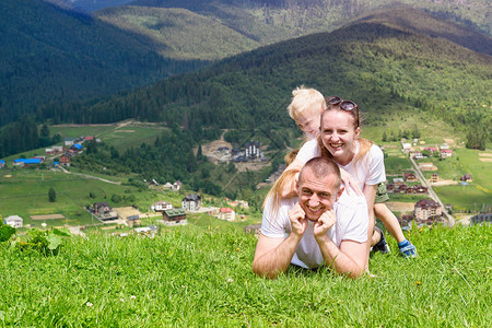 快乐的父亲母亲和两个儿子躺在绿草上图片