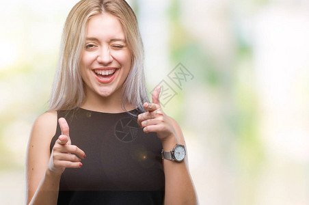 身处孤立背景的金发年轻女子用快乐和有趣的面孔将手指对着相机指着镜头图片